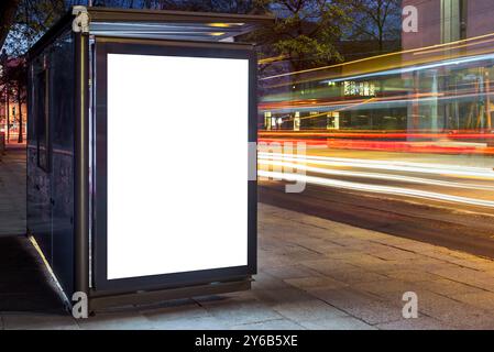 Maquette blanche vierge de boîte à lumière d'affiche verticale dans Un arrêt de bus la nuit Banque D'Images