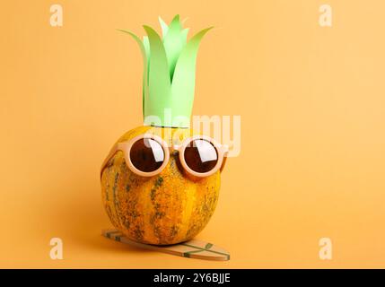 Citrouille d'Halloween dans des lunettes de soleil avec planche de surf sur fond orange Banque D'Images