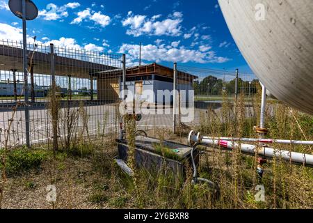 Station-service inactive et abandonnée, distributeurs inactifs, fenêtres arborées, zone clôturée, ancienne gare dans le centre-ville par l'autoroute Banque D'Images