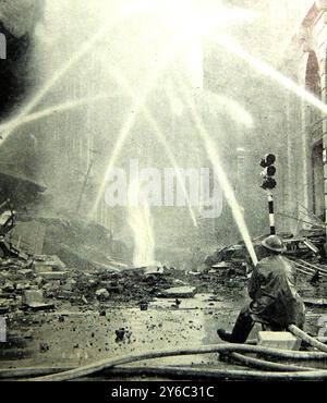 WWII- 1940 Un pompier londonien pulvérise les flammes après un attentat à la bombe incendaire.. - Zweiter Weltkrieg – 1940. Ein Londoner Feuerwehrmann löschte die Flammen nach einem Brandbombenangriff. - Seconde Guerre mondiale - 1940 un pompier londonien a terminé les flammes après une attaque à la bombe incendiaire. Banque D'Images