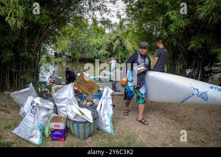 Nettoyage volontaire d'un canal à Samutprakarn, Thaïlande Un bénévole portant un Starboard SUP Standup Paddle Boards passe devant des sacs de déchets collectés d'un canal lors d'une journée de nettoyage organisée par Starboard à Samut Prakan, dans la banlieue de Bangkok, Thaïlande, le 21 septembre 2024. Les volontaires participant au nettoyage ont été séparés en deux groupes, où le groupe le plus important ramassait les ordures principalement les déchets plastiques du canal tandis que l'autre groupe ramassait les ordures jetées dans les ruelles voisines. Starboard prête régulièrement des planches SUP pour le nettoyage des canaux, aidant ainsi les communautés à se réunir pour nettoyer et re-nettoyer Banque D'Images