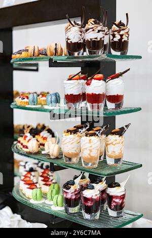 Différents types de desserts sucrés, mousses. Buffet de desserts avec mousse au chocolat blanc et noir avec des fruits dans un pot Banque D'Images