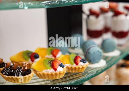 Délicieuse mini tarte aux fruits sur une table de buffet exposée sur un stand de pâtisseries avec assortiment de pâtisseries fruitées avec un accent sélectif lors d'une réception de mariage Banque D'Images