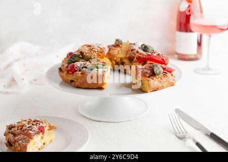 Un gâteau festif avec des fruits confits et des noix sur un stand à gâteau, accompagné d'un verre de vin Banque D'Images