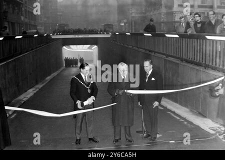 LESLIE FARMILOE COUNCILLOR ET LORD MORRISON OUVRENT UN PASSAGE SOUTERRAIN de 1 MILLION de livres À LONDRES 21 JANVIER 1964 UN PASSAGE SOUTERRAIN DE 1 MILLION de livres A OUVERT LONDRES ; Lord Morrison of Lambeth (au centre) surveillé par le maire de Westminster, le conseiller Leslie Farmiloe (à gauche) et M. A Wicks (à droite), président du London County Council, coupe la bande entre Waterloo Bridge et Kingsway, à l'extrémité du tunnel du pont Waterloo Bridge. La conversion de l'ancien tunnel de tramway de Londres en passage souterrain à sens unique a pris 15 mois. Il mesure un peu plus d'un tiers de mille de long et pourra prendre 1 500 véhicules et une heure. F Banque D'Images