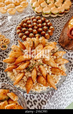 Une table magnifiquement agencée avec un assortiment d'entrées comprenant des empanadas, des mini hamburgers et diverses pâtisseries. Banque D'Images