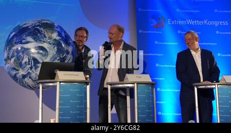 Hambourg, Allemagne. 25 septembre 2024. Eckart von Hirschhausen (gauche-droite), Stiftung Gesunde Erde - Gesunde Menschen gGmbH (GEGM) médecin, auteur et présentateur TV, tient un globe aux côtés de Sven Plöger, météorologue et auteur, et Tobias Fuchs, directeur du climat et de l'environnement au Service météorologique allemand (DWD), lors de la conférence de presse d'ouverture du 14e Congrès météorologique extrême à l'Université Hafencity de Hambourg. Un des thèmes du congrès de trois jours est le thème des conditions météorologiques extrêmes dans le changement climatique. Crédit : Marcus Brandt/dpa/Alamy Live News Banque D'Images