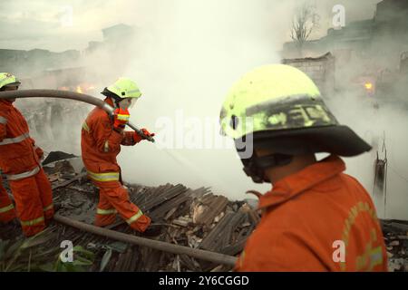 Les pompiers effectuant la phase de refroidissement après un incendie ont incendié des centaines de maisons dans un quartier dense de Jakarta, en Indonésie. Banque D'Images