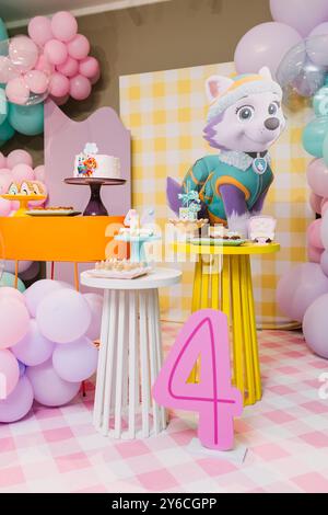 Configuration colorée de fête d'anniversaire avec des ballons, des gâteaux et une grande décoration de personnage de dessin animé, célébrant le quatrième anniversaire d'un enfant. Banque D'Images