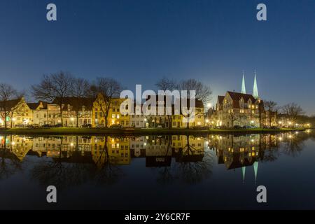 Bâtiments résidentiels reflétés dans la lumière du soir dans la rivière Trave. Schleswig-Holstein, Allemagne Banque D'Images