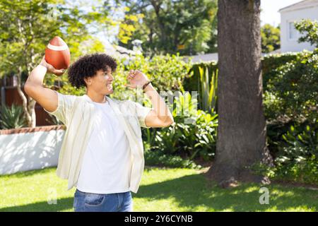 Lancer le football, l'homme profitant de l'activité de plein air dans le jardin arrière avec des arbres Banque D'Images