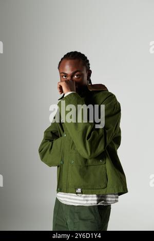 Un jeune homme vêtu de vêtements verts tendance met en valeur son style unique tout en frappant une pose. Banque D'Images