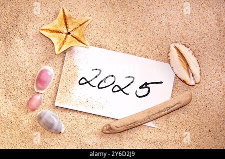 2025, écrit sur une note dans le sable avec des coquillages, vacances voyage carte du nouvel an Banque D'Images