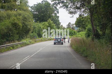 Véhicule tout-terrain se déplaçant lentement derrière deux cyclistes placés côte à côte. Situation du trafic routier local Banque D'Images