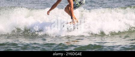 Vue de face d'un homme attrapant une vague à cheval sur un kite board hydrofooting dans l'océan de près. Banque D'Images