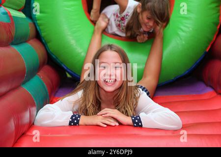 Fille mignonne dans une maison gonflable colorée de rebond. s'amuser à une fête d'anniversaire d'enfants avec des enfants en arrière-plan Banque D'Images