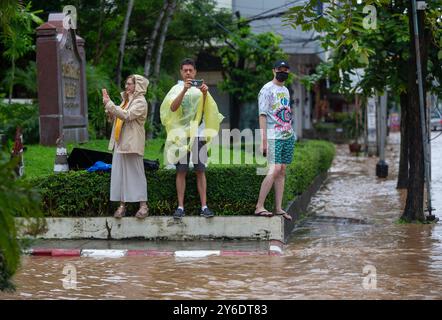 Chiang mai, Thaïlande. 25 septembre 2024. Les touristes étrangers prennent des photos d'une rue inondée dans la région de Chang Khlan en raison de la rivière Ping qui déborde dans les zones urbaines après des précipitations continues à Chiang mai. Les inondations dans la zone urbaine de Chiang mai, en particulier dans le district de Chang Khlan, ont résulté de plusieurs jours consécutifs de fortes précipitations, provoquant une élévation du niveau de l'eau dans la rivière Ping et un débordement de ses rives. Les eaux de crue ont inondé des maisons et plusieurs routes. Les autorités travaillent maintenant à drainer l'eau et surveillent de près la situation. Crédit : SOPA images Limited/Alamy Banque D'Images