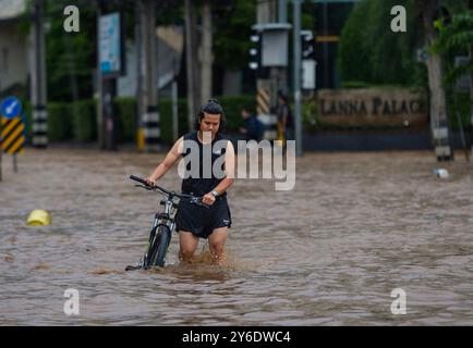 Un homme avec un vélo marche le long d'une rue inondée dans la région de Chang Khlan après que la rivière Ping a débordé dans les zones urbaines à la suite de pluies continues à Chiang mai. Les inondations dans la zone urbaine de Chiang mai, en particulier dans le district de Chang Khlan, ont résulté de plusieurs jours consécutifs de fortes précipitations, provoquant une élévation du niveau de l'eau dans la rivière Ping et un débordement de ses rives. Les eaux de crue ont inondé des maisons et plusieurs routes. Les autorités travaillent maintenant à drainer l'eau et surveillent de près la situation. À partir de 15 h, le niveau d'eau à la station P1 près du pont Nawarat avait Banque D'Images