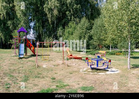 Une aire de jeux confortable et sûre dans le parc. Une variété d'attractions colorées. Pelouse ensoleillée ouverte pour les enfants. Matin ensoleillé chaud et lumineux. Le concept de phy Banque D'Images