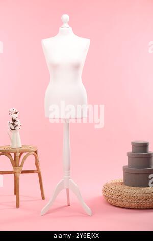 Mannequin féminin, pouf, boîtes, tabouret et vase avec des fleurs de coton sur fond rose Banque D'Images