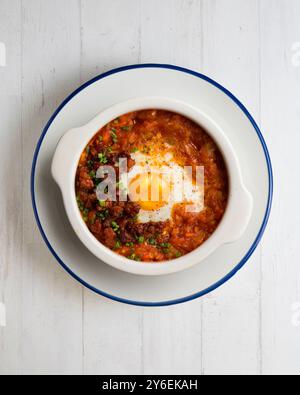 Tapa espagnole d'oeuf cuit au four avec chorizo ​​and tomate. Table vue sur le dessus avec décorations. Banque D'Images