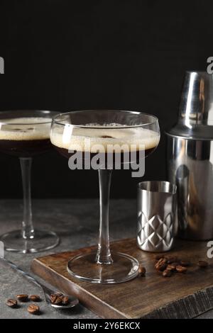 Verres de délicieux martini espresso et grains de café sur la table texturée sombre, gros plan Banque D'Images