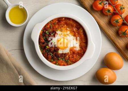 Tapa espagnole d'oeuf cuit au four avec chorizo ​​and tomate. Table vue sur le dessus avec décorations. Banque D'Images