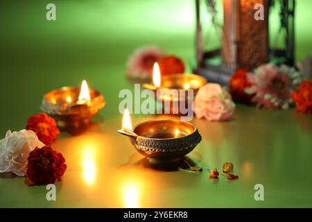 Célébration de Diwali. Lampes Diya et belles fleurs sur fond vert Banque D'Images