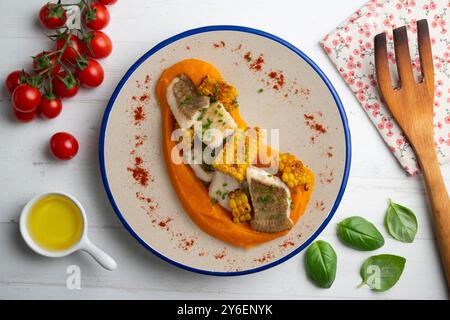 Délicieux poisson de sole avec crème de carottes et maïs. Table vue sur le dessus avec décorations. Banque D'Images