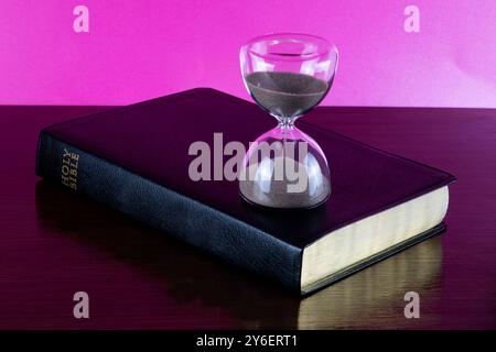 Bible chrétienne sur une étagère en bois poli avec sablier en verre Banque D'Images