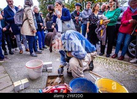 Schwerin, Allemagne. 25 septembre 2024. Gunter Demnig, artiste de Cologne, pose des pierres de trébuchement à la mémoire des victimes du national-socialisme. La famille Löwenthal et ses enfants Renate (12 ans) et Eddie (5 ans), morts dans le camp de concentration d’Auschwitz, seront commémorés à Demmlerplatz. Au total, douze nouvelles Stolpersteine seront posées à Schwerin. Demnig posa les pierres avec des plaques de laiton devant les derniers lieux de résidence du peuple. Crédit : Jens Büttner/dpa/Alamy Live News Banque D'Images