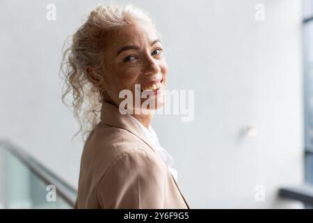 Femme souriante dans la tenue d'affaires regardant avec confiance à la caméra dans le cadre de bureau, espace de copie Banque D'Images