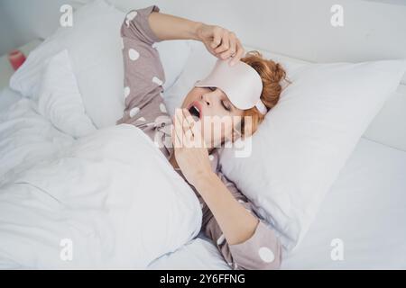 Photo de jolie femme joyeuse masque de vêtements de nuit bâillant ayant une chambre de repos à l'intérieur maison à la maison Banque D'Images