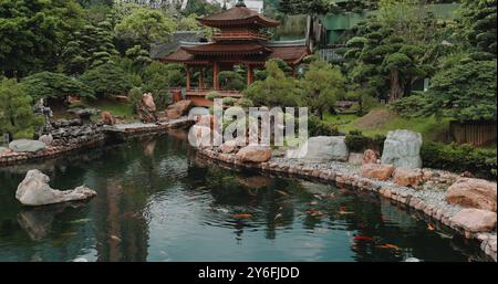 Jardin japonais serein avec pavillon en bois, étang à carpes koï, verdure luxuriante, Banque D'Images