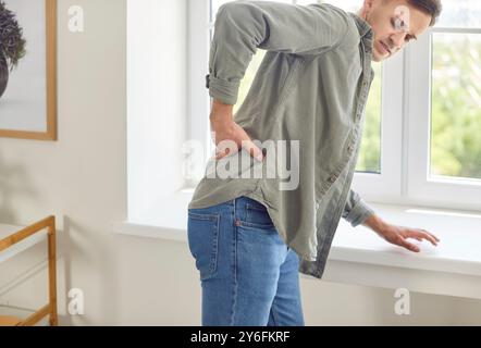 Homme souffrant de maux de dos à la maison en raison d'une blessure ou d'une maladie Banque D'Images