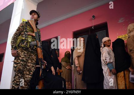 Srinagar, Inde. 25 septembre 2024. Les électrices sont alignées pour voter tandis que le personnel de sécurité surveille le bureau de vote dans la zone de Charari Sharief du district de Budgam le 22 septembre 2024. Le scrutin a commencé à 7 heures du matin et se terminera à 18 heures, avec plus de 2,5 millions d'électeurs prêts à voter dans six districts - trois dans la vallée du Cachemire et trois dans la division de Jammu. Il s'agit du premier scrutin d'Assemblée dans la région sensible depuis que son statut spécial et son statut d'État ont été supprimés il y a cinq ans. (Photo de Danish Showkat/ Credit : Sipa USA/Alamy Live News Banque D'Images