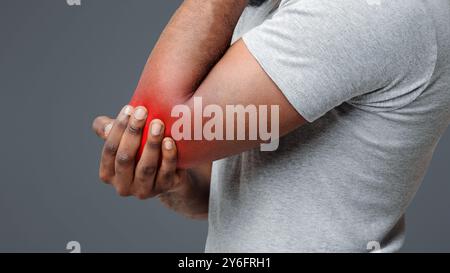 Recadré d'homme afro frottant son coude blessé Banque D'Images