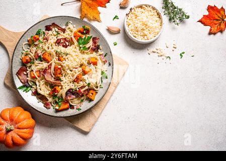 Pâtes à la citrouille et au bacon au parmesan râpé. Pâtes à la citrouille spaghetti maison et feuilles d'érable sur fond blanc, vue de dessus, espace de copie. Mers Banque D'Images