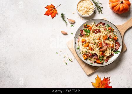 Pâtes à la citrouille et au bacon au parmesan râpé. Pâtes à la citrouille spaghetti maison et feuilles d'érable sur fond blanc, vue de dessus, espace de copie. Mers Banque D'Images