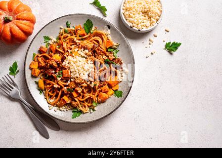 Pâtes spaghettis bolognaises à la citrouille et au bœuf avec parmesan râpé. Pâtes de citrouille et de viande spaghetti maison sur fond blanc, vue de dessus, copie Banque D'Images