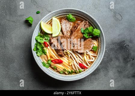 Soupe vietnamienne Pho Bo. Bol de délicieuse soupe asiatique fraîche avec nouilles de riz, viande de bœuf, herbes, pousses de soja et Chili, vue de dessus. Cuisine asiatique, confort Banque D'Images
