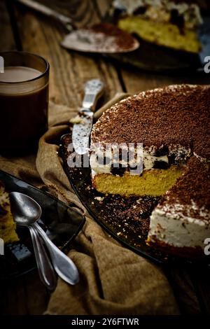 cheesecake avec pruneaux et chocolat coupé en morceaux sur une table en bois. Banque D'Images