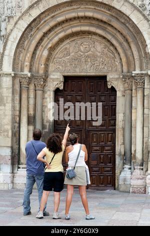 Trois visiteurs apprécient les détails complexes de l'entrée romane de la basilique San Isidoro à León, en Espagne. Banque D'Images