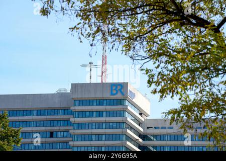 Munich, Bavière, Allemagne - 23 septembre 2024 : bâtiment du Bayerischer Rundfunk BR à Munich, avec le logo bleu caractéristique BR et le panneau ARD, ainsi que des antennes radio sur le toit, encadrées par des arbres *** Das Gebäude des Bayerischen Rundfunks BR in München, mit der charakteristischen blauen BR-logo und ARD-Zeichen, sowie Funkantennen auf dem Dach, umrahmt von Bäumen Banque D'Images