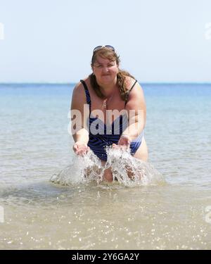 Bain de femme en surpoids dans la mer et les éclaboussures Banque D'Images