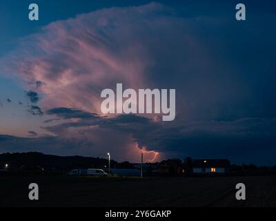 La foudre rose descend d'un majestueux nuage de tempête au-dessus de la campagne de Transylvanie, en Roumanie dans la soirée. Banque D'Images