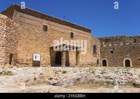 Église historique en pierre avec une entrée et une croix sous un ciel bleu clair, Castillo de Penarroya, château, forteresse, Penarroya, province de Ciudad Real, Banque D'Images