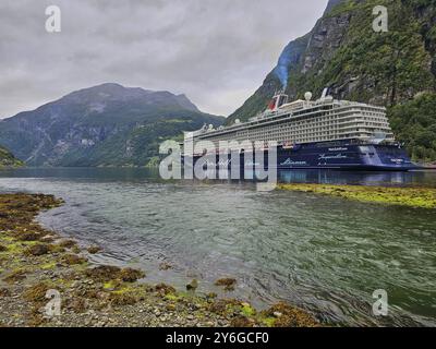 Un grand bateau de croisière, Mein Schiff 6, se trouve dans le fjord, entouré de montagnes verdoyantes sous un ciel nuageux, Geiranger, Geiranger Fjord, Stranda, Romsdal Banque D'Images