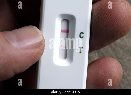 Une faible ligne rouge indique un résultat positif d’un test de flux latéral covid. Banque D'Images