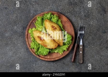 Nourriture, nourriture, PÉRUVIEN plat traditionnel CHILIEN PAPA RELLENA viande farcie purée de pommes de terre sur assiette en bois Banque D'Images